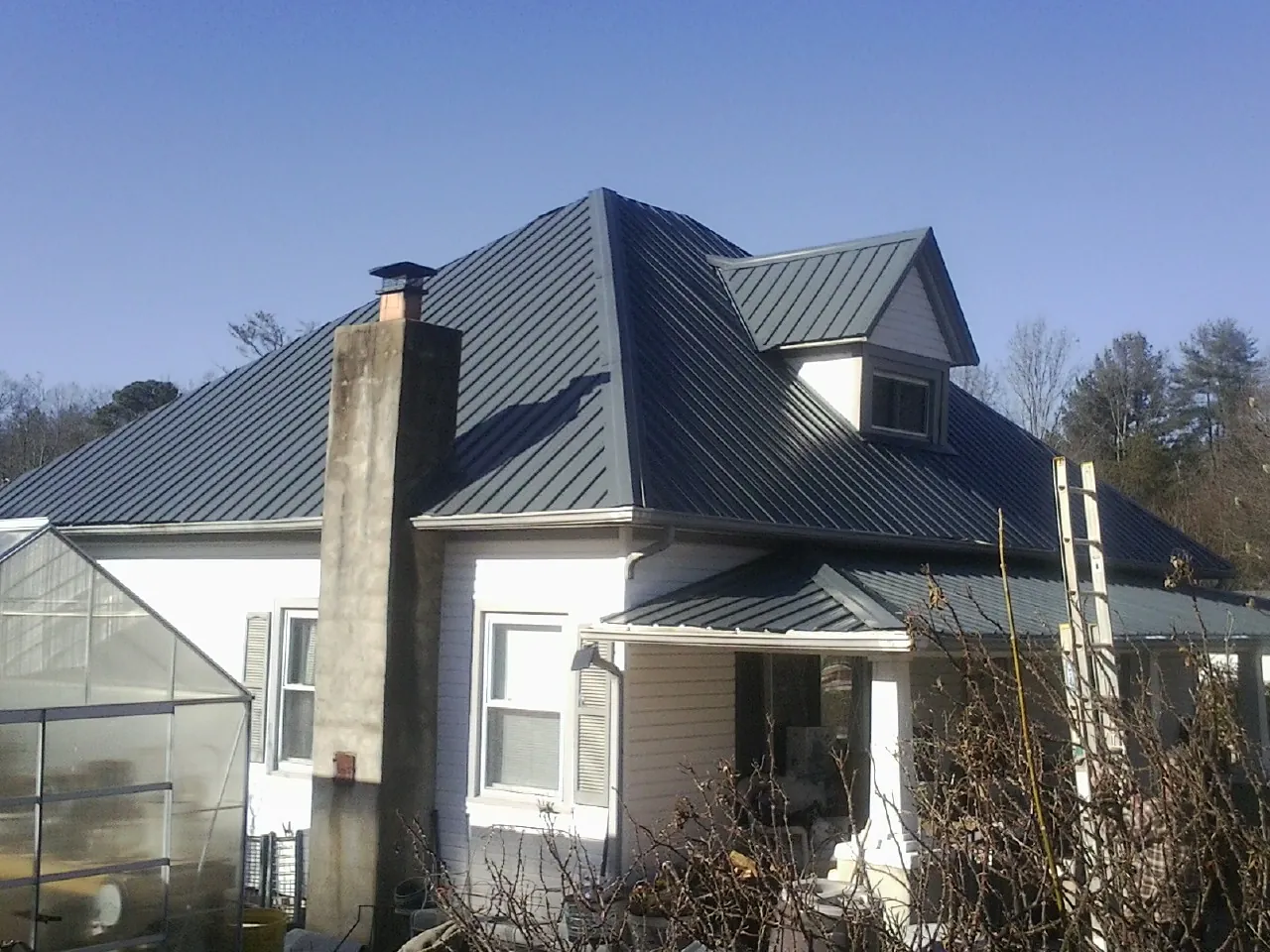 Dark blue standing seam metal roof on a white farmhouse with dormer — Slate & Tile Roof Repair by Roofing Brothers in Monroe Bridge