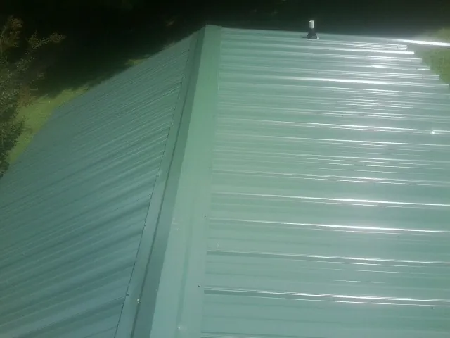 New green metal panels meeting at the ridge of a roof — Flat Roof Repair work by our crew in Monroe Bridge