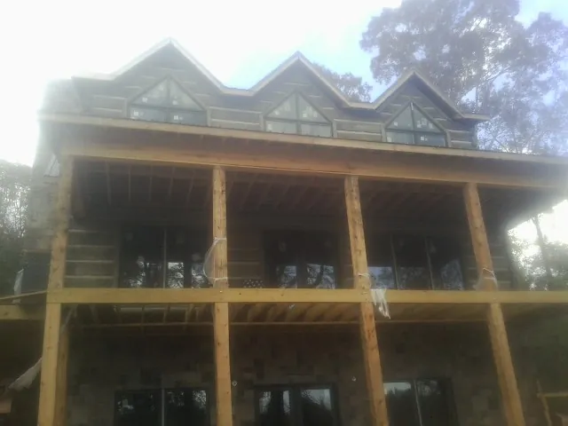 Dormers and porch framing on a large log home under construction — Roof Coating work by our crew in Monroe Bridge