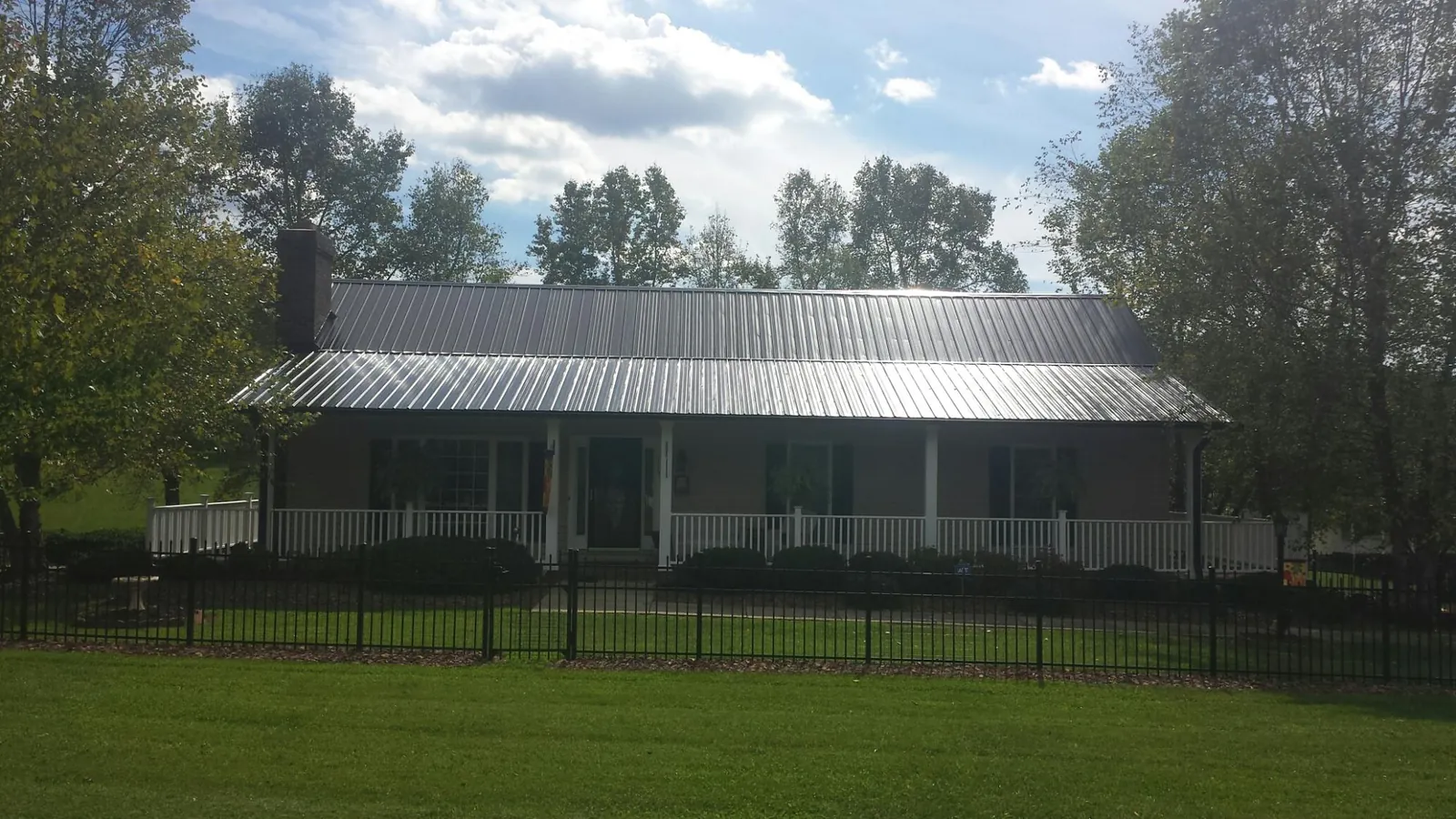Gray metal roof on a brick ranch with a full width front porch — Gutter Guard Installation work by our crew in Monroe Bridge