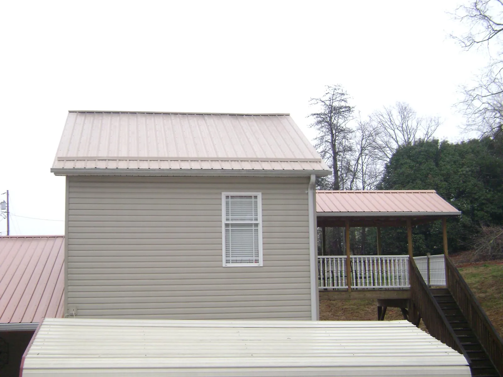 Tan metal roofs on a two story addition and attached porch, from a Roof Replacement job in Monroe Bridge