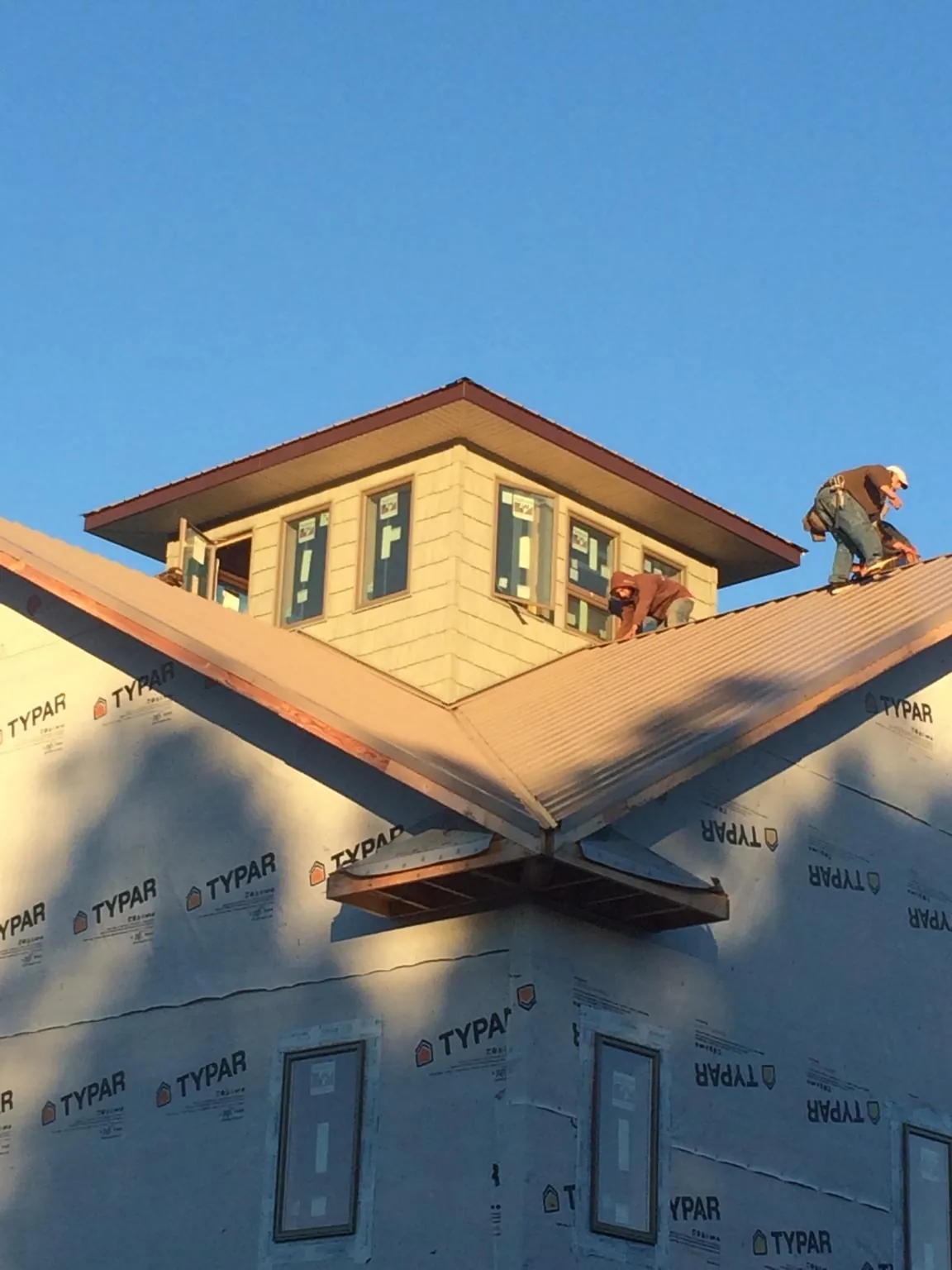 Roofers working around a rooftop cupola on a new metal roof at sunset — Roof Waterproofing in Monroe Bridge by Roofing Brothers
